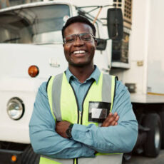 Man, portrait and outdoor at warehouse with confidence for logistics, gear for safety and smile for health. Male driver, happy and outside factory with semi truck for supply chain, job with transport